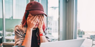 Young woman stressed while working on laptop.