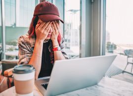 Young woman stressed while working on laptop.