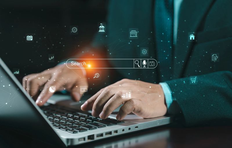 Hands typing on laptop keyboard with virtual search bar