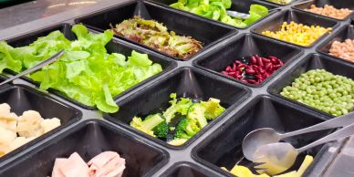 Variety of fresh salad ingredients in trays.