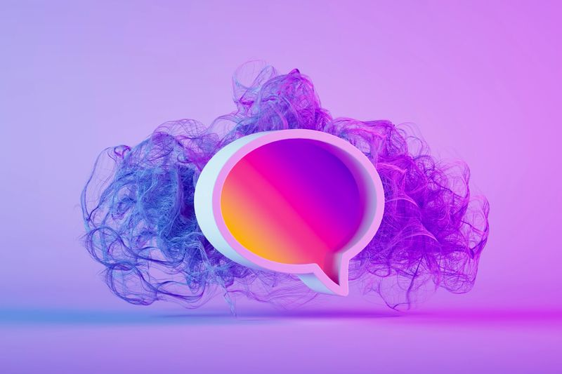 A high-quality 3D rendering of a large, colorful speech bubble featuring a smooth pink, orange, and purple gradient. The icon floats within an abstract cloud of purple and blue smoke, creating a sense of energy and modern movement. This visual represents creative digital communication, social media interaction, and innovative messaging platforms. It is an ideal background for themes of customer feedback, viral marketing, global connectivity, and modern branding in a professional yet artistic style.