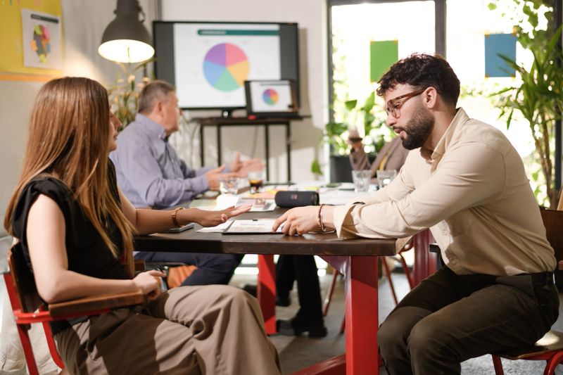 Business professionals engage in a strategic meeting in a contemporary office space. They analyze charts and data to make informed decisions. The atmosphere is focused and collaborative.