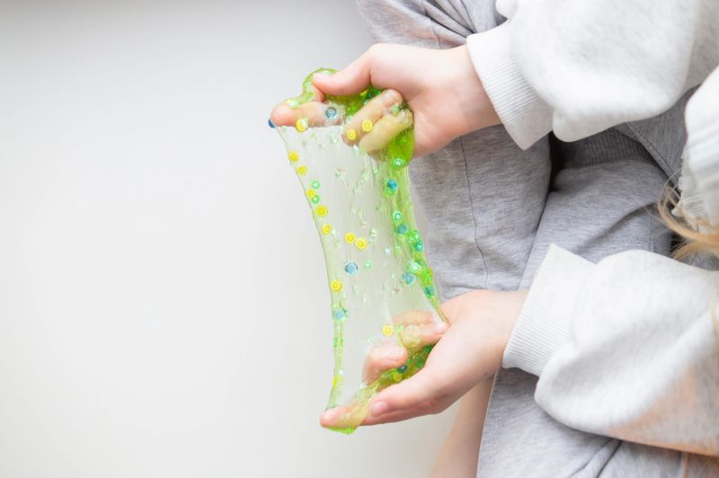 A child playing with slime, stretching, squeezing, and exploring its texture. Playing at home, leisure.