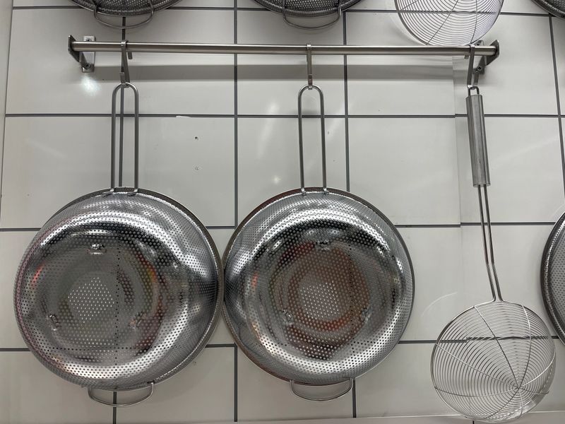 collection of stainless steel kitchen utensils hanging on a wall