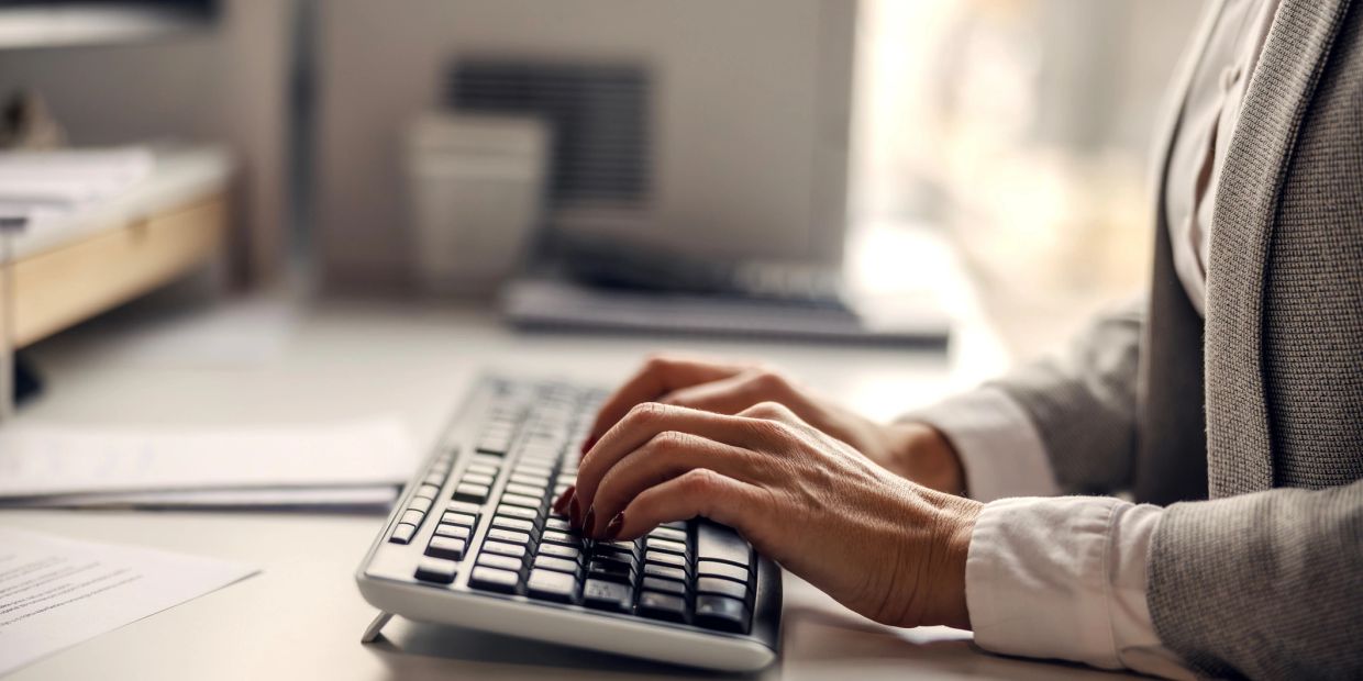 Close-up of hands typing on a keyboard in an office setting.