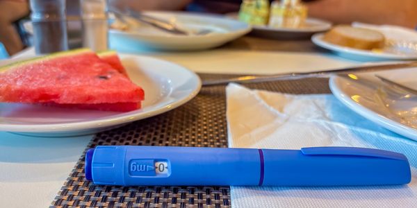 A close-up image of a GLP-1 injection pen in a home setting, representing medically supervised weigh