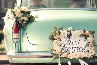 A classic car decorated with flowers and a Just Married sign.