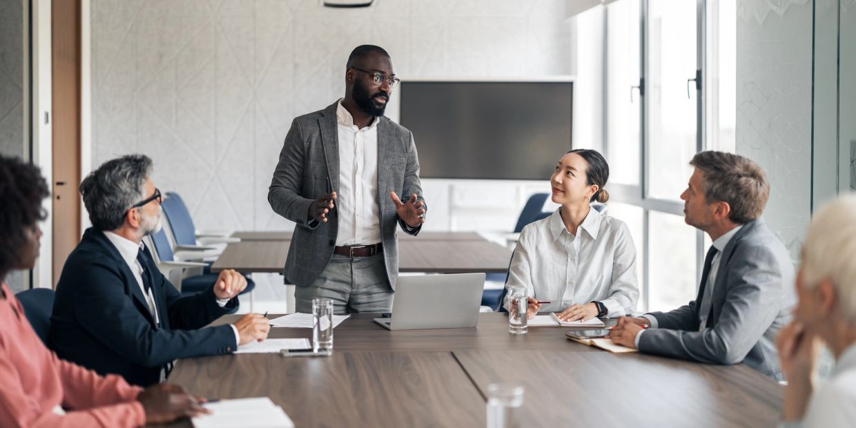 Man presenting to colleagues at a conference table.