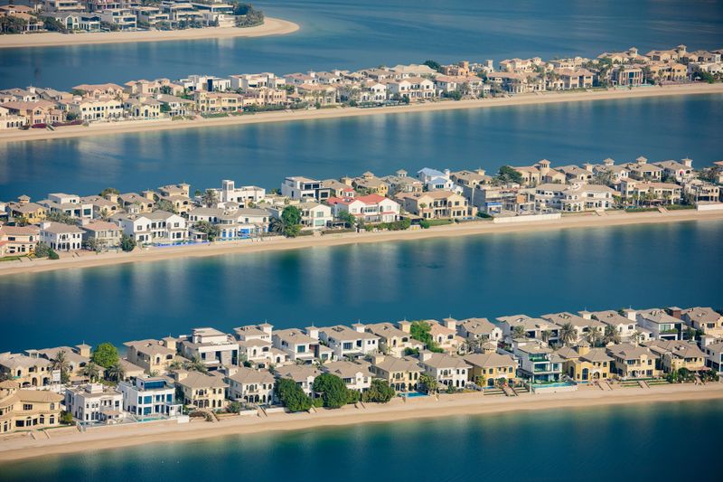 Palm Jumeirah in Dubai presenting an aerial view of numerous luxury residential villas lining the man-made island's waterfront, reflecting wealth and exclusive real estate development