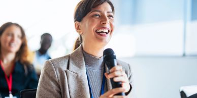 Woman speaking with a microphone at a conference.