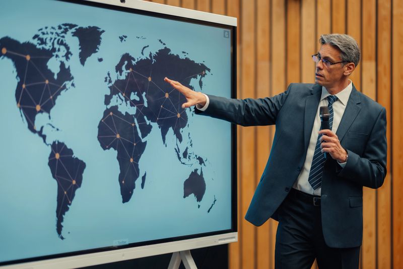 Businessman presenting global business strategy during conference, using a digital world map with a connected network