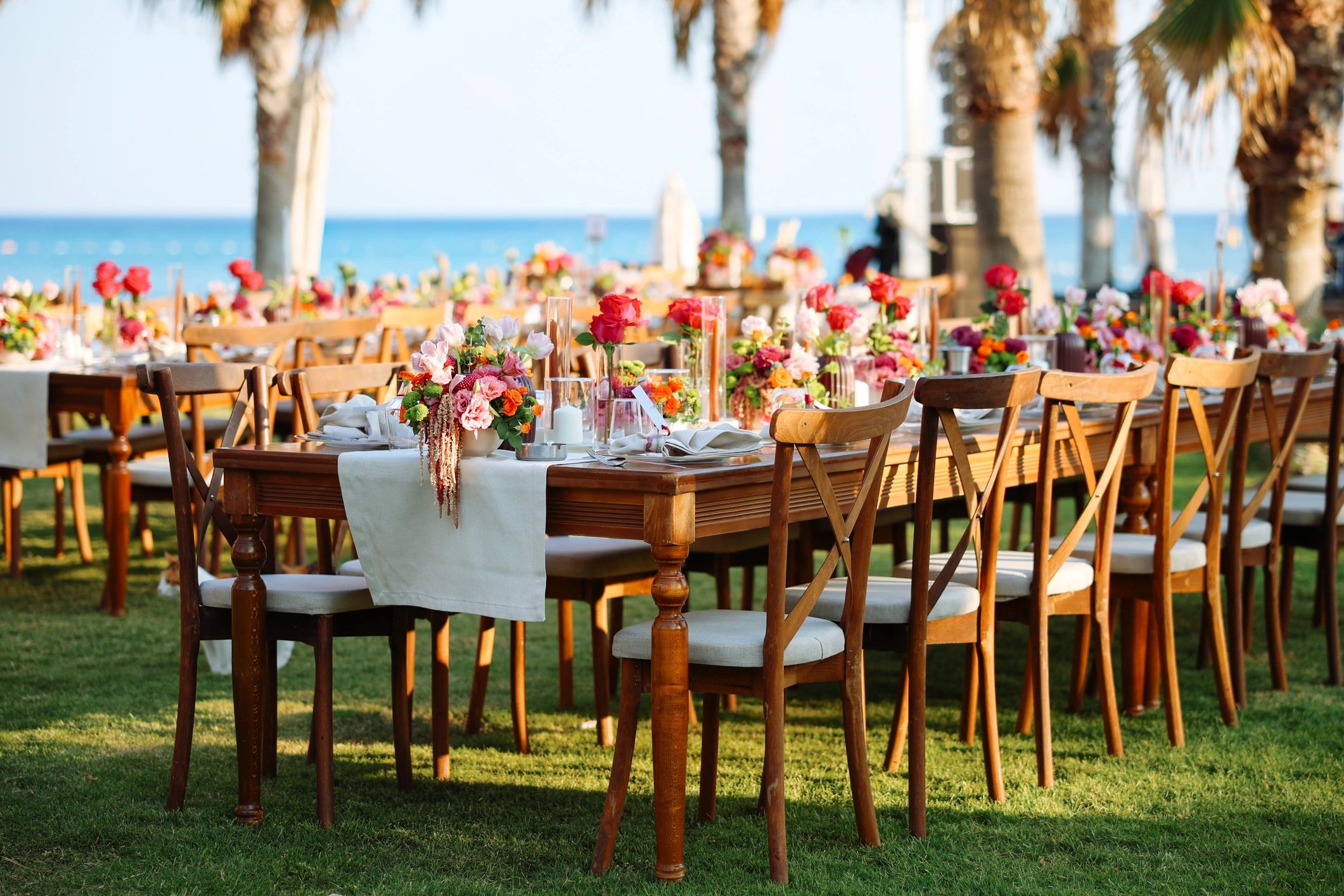 Elegant outdoor dining setup with floral centerpieces near the sea.