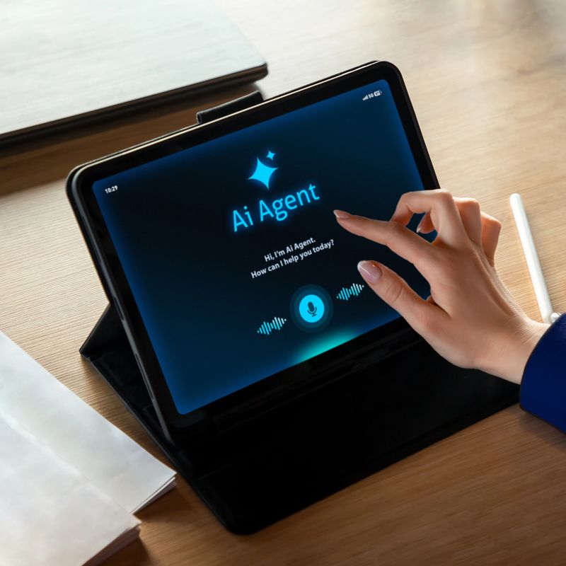 Professional businesswoman working at a desk while interacting with an AI assistant on a tablet screen. The scene shows a modern office environment with notebook, laptop, and digital tools, representing productivity, smart technology, and digital transformation in business. Ideal for concepts related to artificial intelligence, remote work, automation, business innovation, and modern office lifestyle.Usage:Business presentations, technology websites, corporate marketing, fintech, SaaS platforms, AI services, productivity apps, digital transformation campaigns.