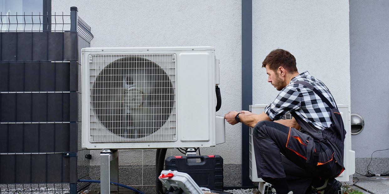 Technician repairing an outdoor air conditioning unit.