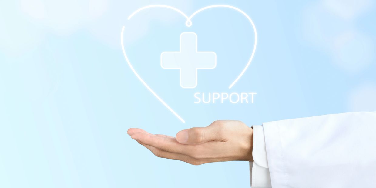 Hand supporting glowing heart with medical cross symbol.