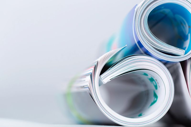 Several rolled magazines placed close together on a flat surface, showing colorful pages.