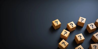 Wooden blocks with question marks on a dark surface.
