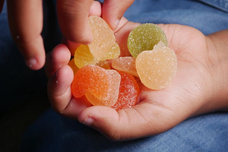 A child enjoys various colorful gummy candies while playing outside.