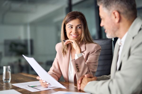 Businesswoman smiling while discussing documents with a colleague.