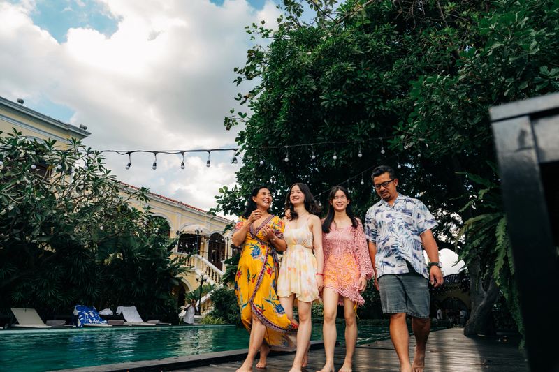 Asian family walking together by pool at luxury resort