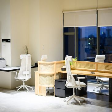Modern office workspace with white chairs and wooden desks.