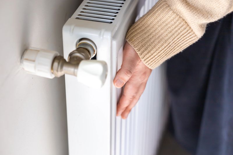 Female Hands Touching Warm Radiator. House In Cold Winter. Radiator Heating. Keeping Warm up On Heating System. Central Heating.