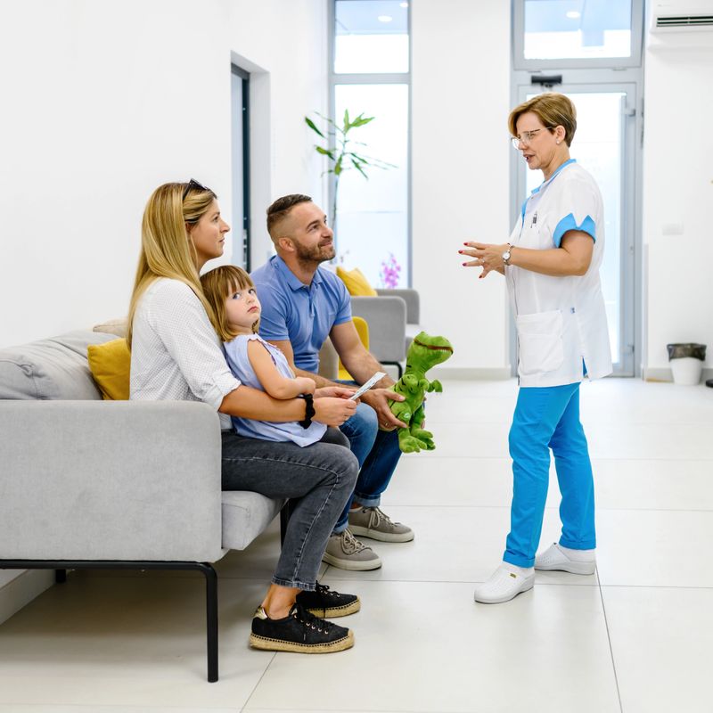 Parents with a daughter talking to a female doctor in a hospital waiting area