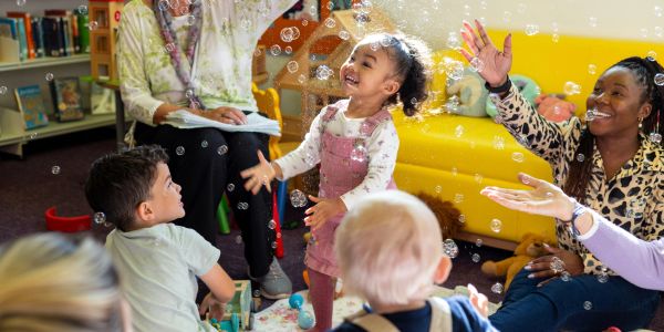 Kids joyfully playing with bubbles in a classroom.