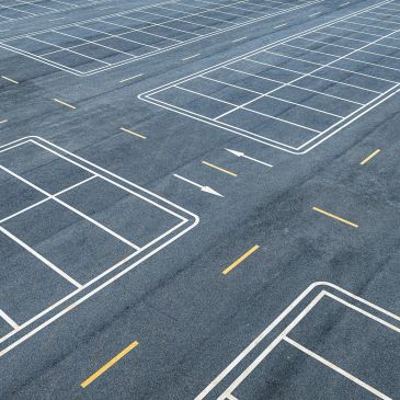 Empty parking lot with marked spaces and directional arrows.