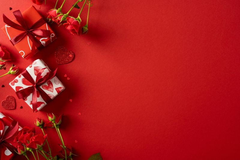 Vibrant red background with wrapped gifts and roses creates a romantic mood perfect for Valentine greetings, promotions, and festive campaigns