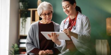 Doctor consulting with an elderly woman using a tablet.