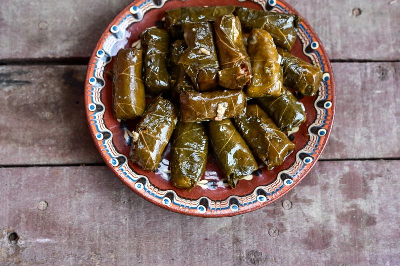Dolmades - stuffed grape leaves  rolls  with rice the Greek way on wooden table .Stuffed greek wine leaves