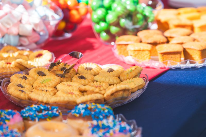 Cream-filled cookies arranged on a festive outdoor party table, with frosted cupcakes displayed alongside, creating an inviting dessert spread in natural daylight.