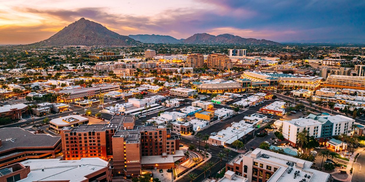Panoramic view of a cityscape at sunset with mountains in the background.