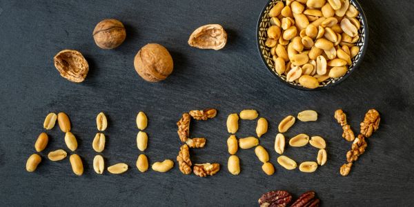 The word ALLERGY spelled out with nuts and nut shells on a black surface.