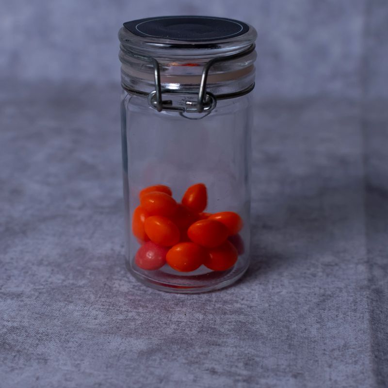 Clear glass food storage jar of orange bite sized candies.