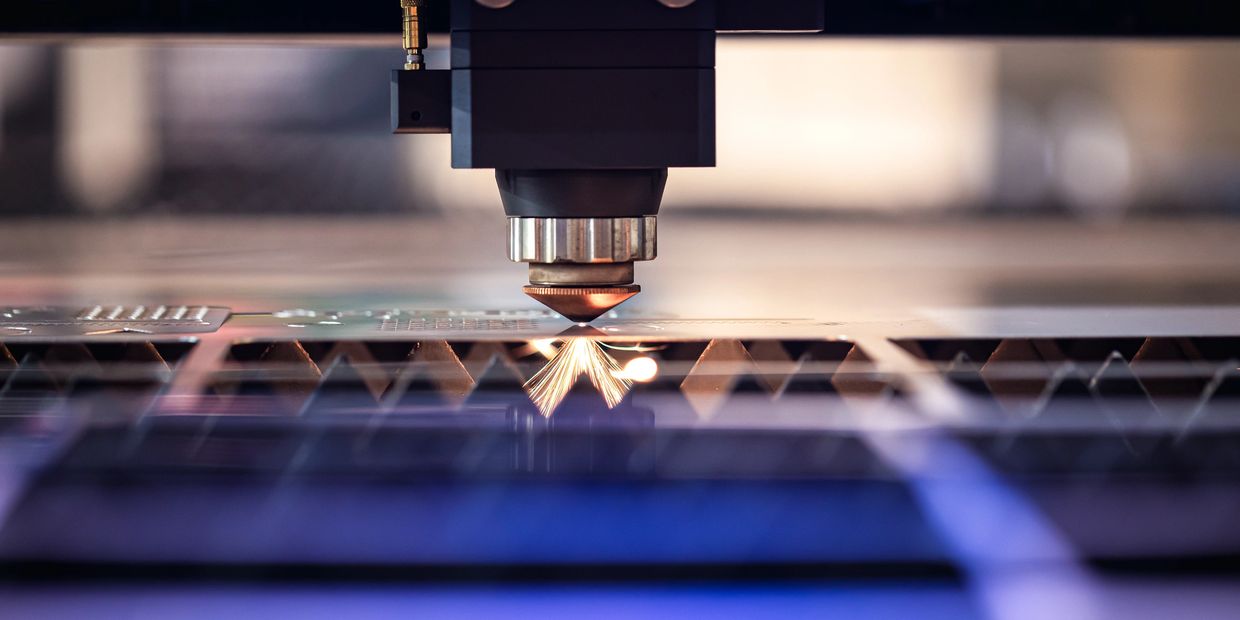 Laser cutting metal sheet with sparks flying.