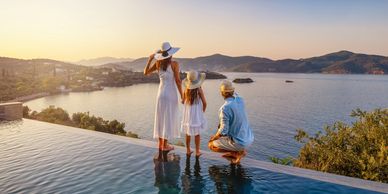 Family enjoying sunset by infinity pool overlooking sea.