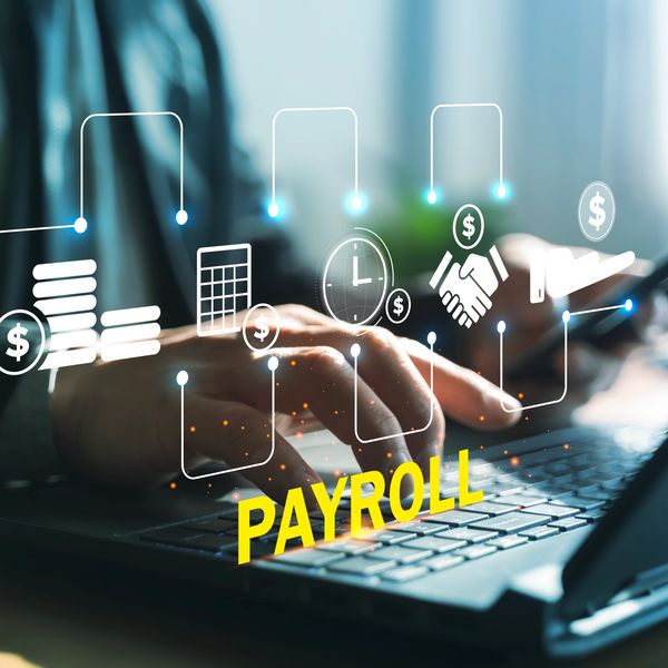 Hands typing on a laptop with payroll icons.