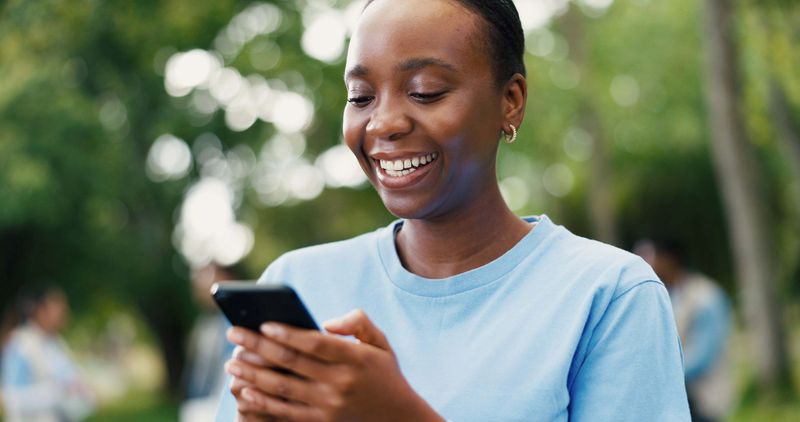 Phone, smile and volunteer with woman in park for charity, community outreach or food drive. App, text message and typing with happy person outdoor for activism, donation or ngo communication
