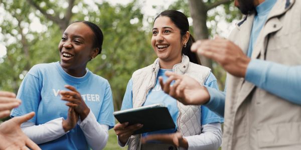 Happy volunteers clapping and smiling outdoors.
