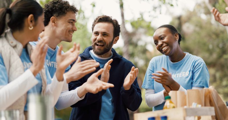 Happy, volunteers and applause for donation, NGO or complete project for community service in forest. Outdoor, celebration and people with food supplies, charity and clapping for achievement in woods