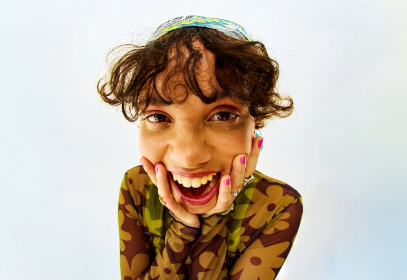 Young woman with curly hair showing joyful expression, embracing wellbeing at a studio
