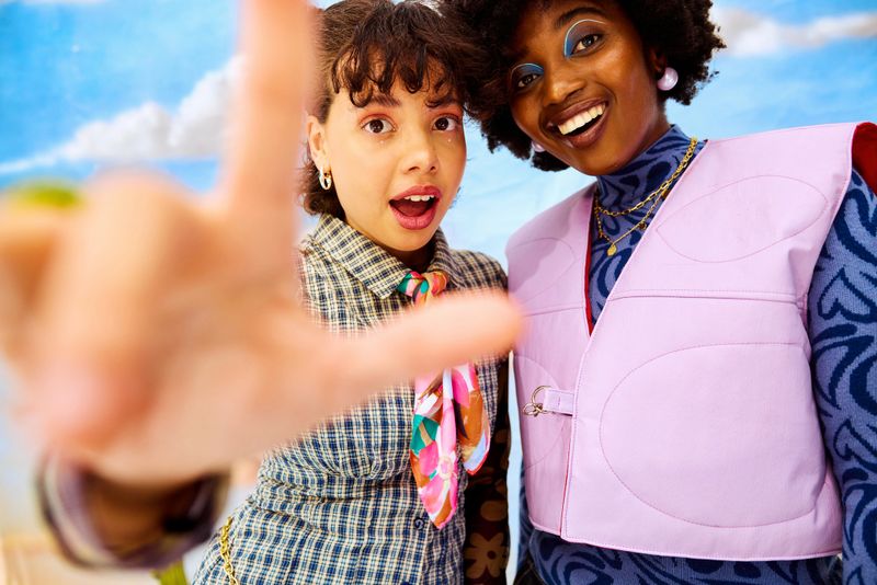 Young multiracial women posing in studio, framing a shot, enjoying genuine friendship