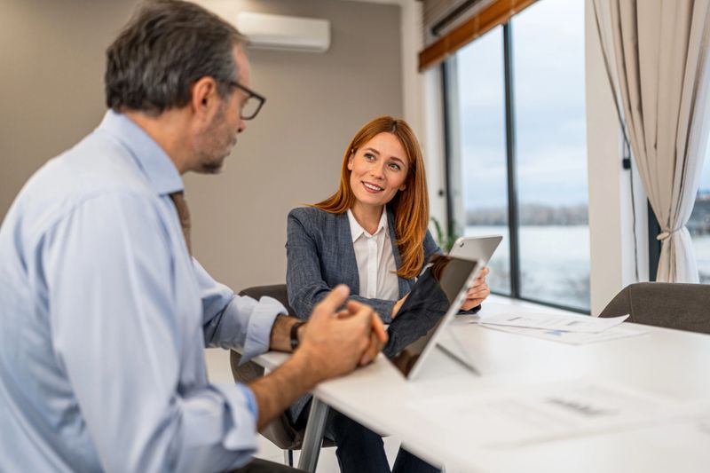 Two business colleagues working together, discussing ideas and planning strategy using a digital tablet in a modern office setup