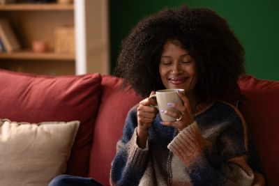 Woman enjoying a warm drink on a cozy couch.