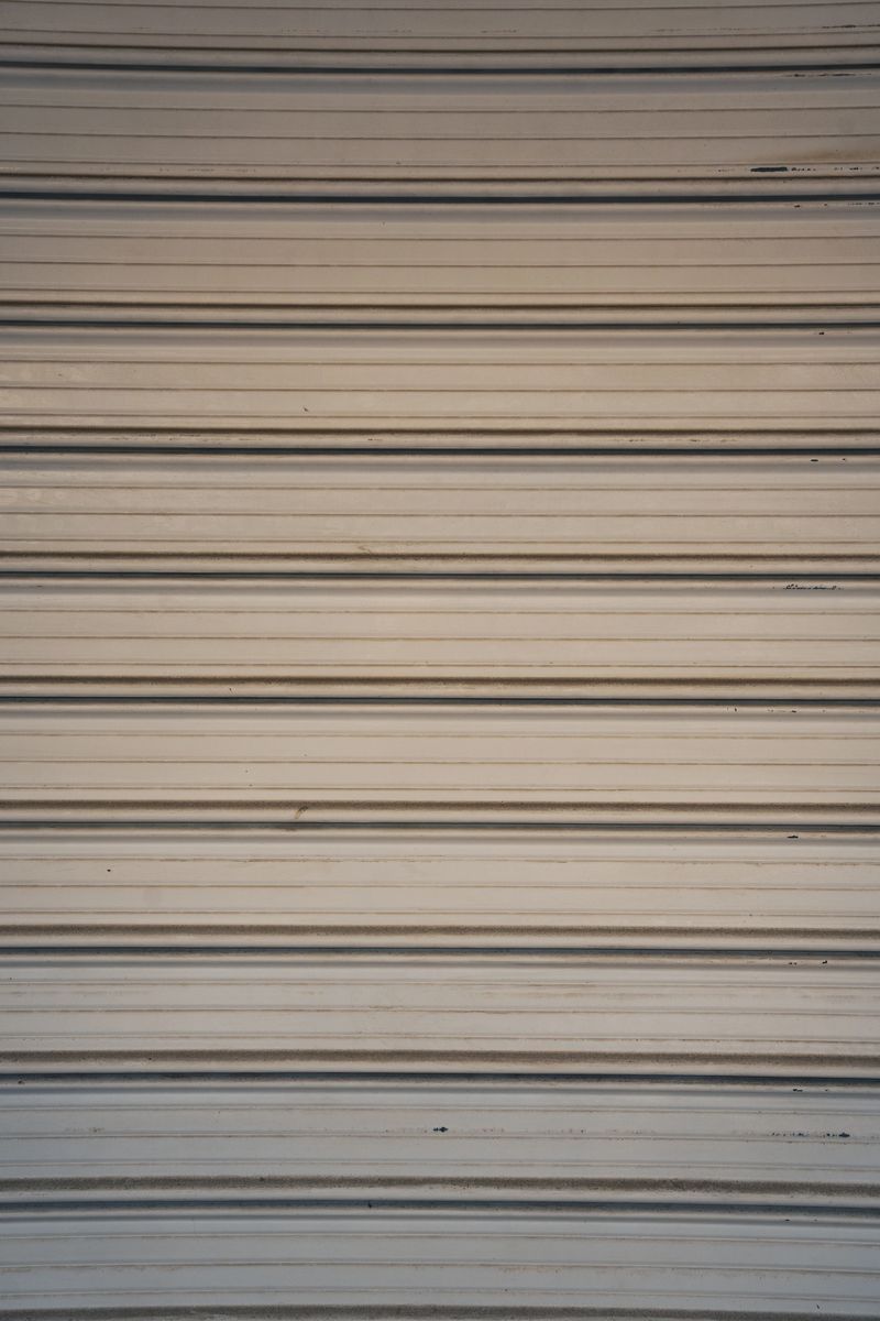 Texture background shows Closed Rolling shutters in front of closed store fronts.