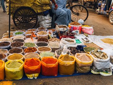 Colorful spices and dried goods at an outdoor market stall.