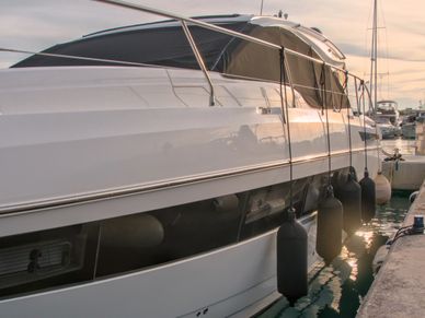 Luxury yacht docked with protective fenders at sunset.