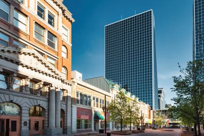 Downtown street with modern and historic buildings under clear sky.